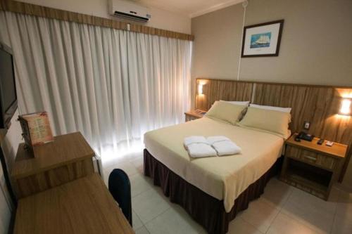 a hotel room with a large bed and a large window at Hotel Colombo in Barra do Garças