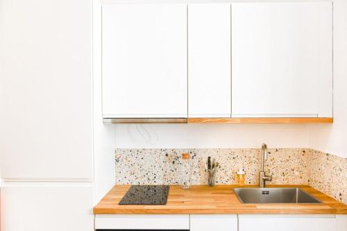 une cuisine avec des armoires blanches et un évier dans l'établissement Le Vauban - Hauteur de Marseille proche de NDG, à Marseille