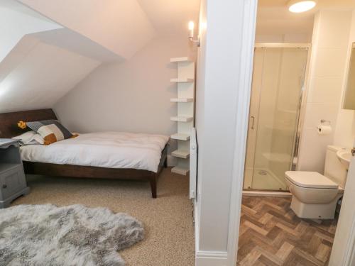 um pequeno quarto com uma cama e um chuveiro em The Quarterdeck em Holyhead
