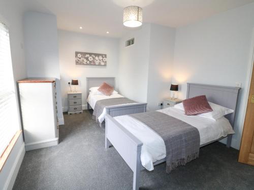 due letti in una stanza con pareti bianche di Corner House Cottage a Ilkeston