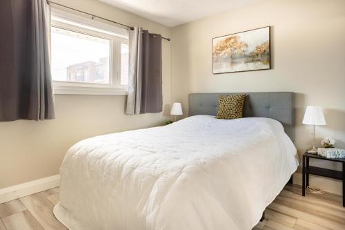 um quarto com uma cama branca e uma janela em ENTIRE 2 BEDROOM APARTMENT DOWNTOWN - u3 em Waterloo