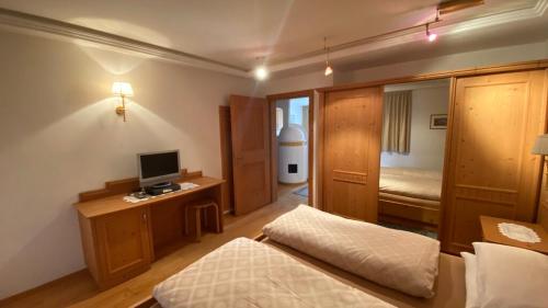 a bedroom with a bed and a desk with a television at Apartments Almiva in Castelrotto