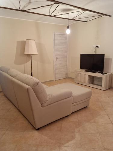 a living room with a white couch and a television at LANGHE PARADISOT in Niella Belbo