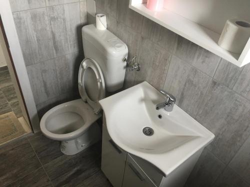 a white bathroom with a toilet and a sink at Motel Capljina in Čapljina