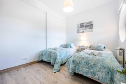 Duas camas num quarto com paredes brancas e pisos em madeira em Casa das Cores em Albufeira