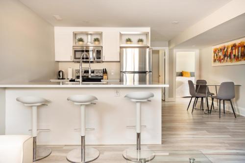a kitchen with white cabinets and bar stools at ENTIRE 2 BEDROOM APARTMENT DOWNTOWN - u1 in Kitchener