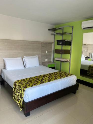 a bedroom with a large bed and a green wall at Hotel Genova Prado in Barranquilla