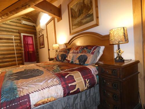 Un dormitorio con una cama y una lámpara en un tocador en Yellowstone Motel - Adults Only - All rooms have kitchens, en West Yellowstone