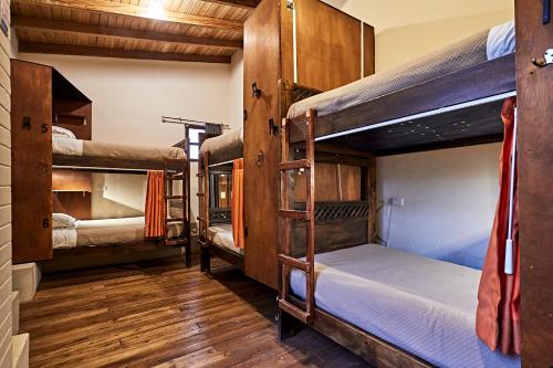a room with three bunk beds and wooden floors at The Secret Garden in Quito