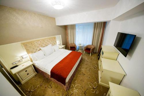 a hotel room with a bed and a flat screen tv at Pleiada Boutique Hotel & Spa in Iaşi