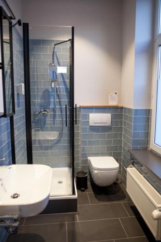 a bathroom with a toilet and a sink and a shower at Storyhotel Bergischer Hof Königswinter in Königswinter