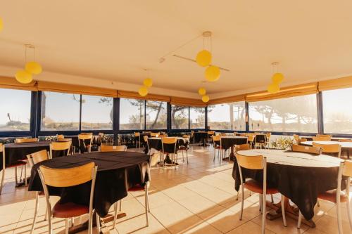 un restaurante con mesas, sillas y ventanas grandes en Apart Hotel Punta Sol, en Punta del Este