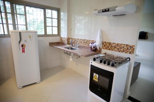 a white kitchen with a stove and a sink at Flats Martinez in Conservatória