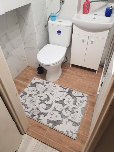 La salle de bains est pourvue de toilettes, d'un lavabo et d'un tapis. dans l'établissement Apartament L14, Mieszkanie dla Wszystkich, à Konin