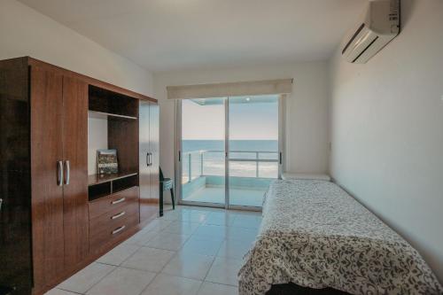 a bedroom with a bed and a view of the ocean at Apart Hotel Punta Sol in Punta del Este
