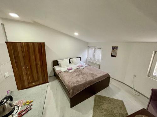 a bedroom with a bed and a wooden cabinet at Apartmani Aleksandra u centru grada in Kragujevac