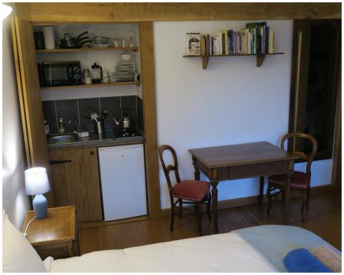 a bedroom with a table and a kitchen with a table and chairs at Sérénité Verte à La Tuilerie Accommodation in La Bazeuge