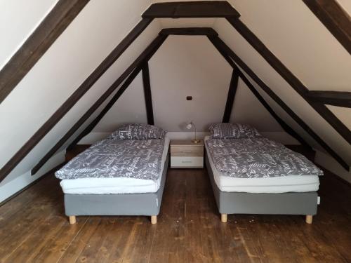 two beds in a attic room with wooden floors at Galerie Vila Lucia 5 -Loft apartmán in Plzeň