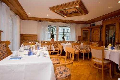 Hotel Garni Promenade في فايسنهورن: غرفة طعام مع طاولات وكراسي بيضاء