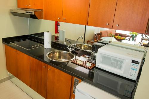 a kitchen with a sink and a microwave at HOTEL ALTAMIRA SUITES in Caracas