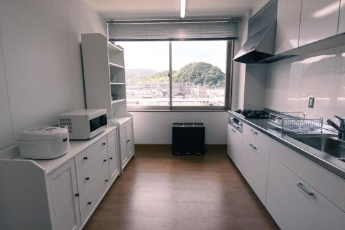 a kitchen with white cabinets and a large window at Manabiamu 4F - Vacation STAY 43666v in Maizuru