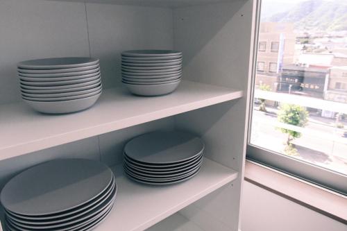 a stack of plates sitting on shelves next to a window at Manabiamu 4F - Vacation STAY 43666v in Maizuru