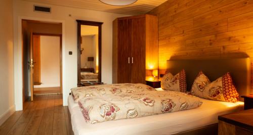 a bedroom with a large bed with a wooden wall at Gasthof - Hotel zur Post in Pöcking