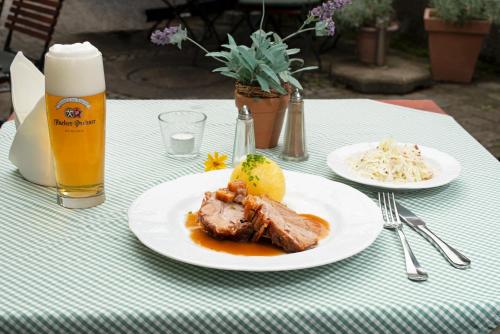 a table with two plates of food and a glass of beer at Gasthof - Hotel zur Post in Pöcking