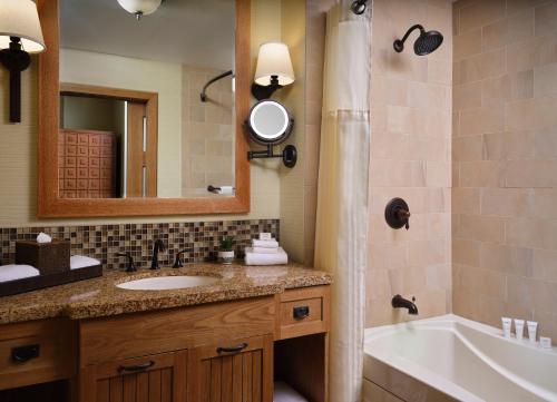 a bathroom with a sink and a tub and a mirror at Hyatt Vacation Club at the Welk, San Diego in Escondido