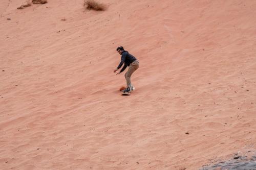 a man riding a skateboard down a sand hill at Wadi Rum Nights in Wadi Rum