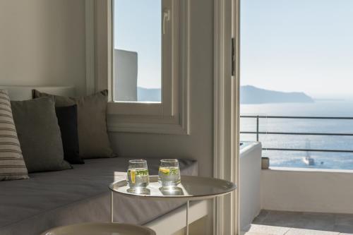 a living room with a couch and two glasses on a table at Porto Fira Suites in Fira