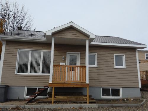 a house with a large deck in front of it at Auberge Jeunesse à Loulou in Lévis
