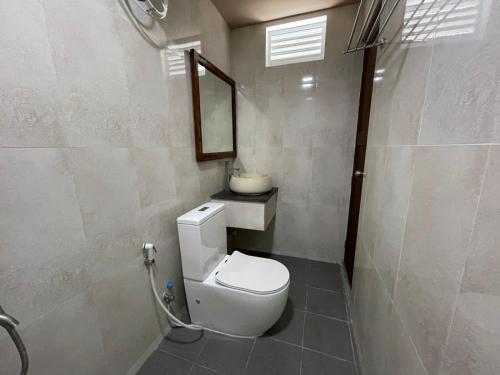 uma casa de banho com um WC branco e um espelho. em Courtyard Guesthouse em Huraa