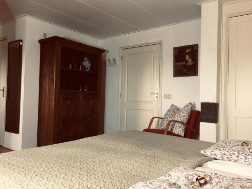 a bedroom with a bed and a cabinet and chairs at Bed and breakfast Zathe De Spieker in Itens