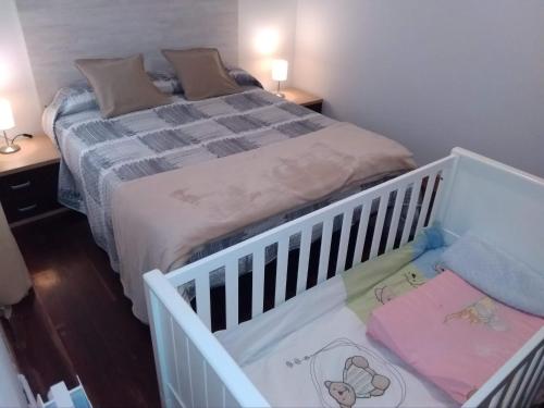 łóżeczko w pokoju z łóżkiem i dwoma stołami w obiekcie Apartamento Portugalete w mieście Portugalete