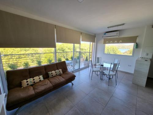 ein Wohnzimmer mit einem braunen Sofa und einem Tisch in der Unterkunft Altos del Potrero Apart in Potrero de los Funes