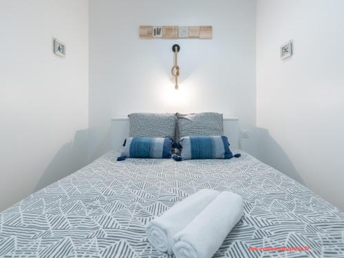 a bed with blue and white sheets and pillows at Au confort du port roannais in Roanne