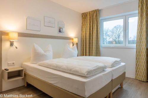 1 dormitorio con 1 cama blanca grande y ventana en Fewo Fiete Whg 4 Haus Kachelotplate, en Hooksiel