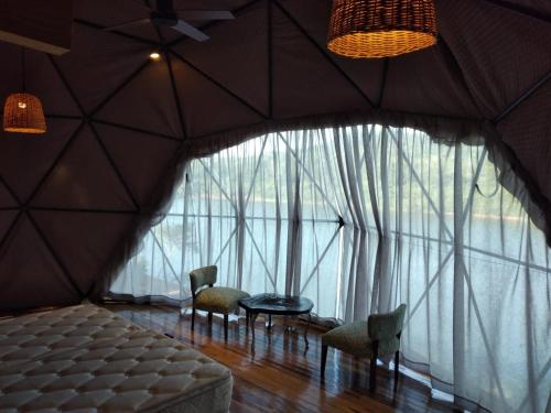 a room with a bed and chairs and a large window at La Mision Mocona - Lodge de Selva in Saltos del Moconá