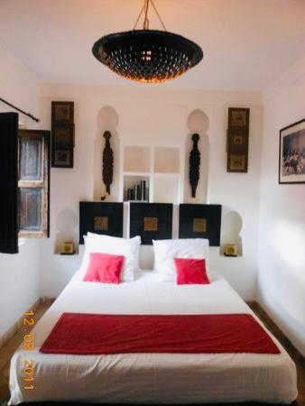 a bedroom with a large white bed with red pillows at Riad Dialna in Marrakech