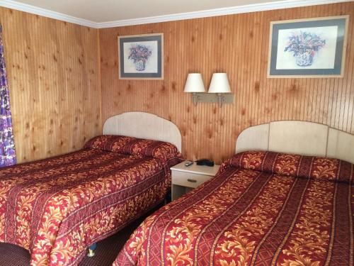 2 camas en una habitación de hotel con paneles de madera en Simpsons Motel, en Rio Grande