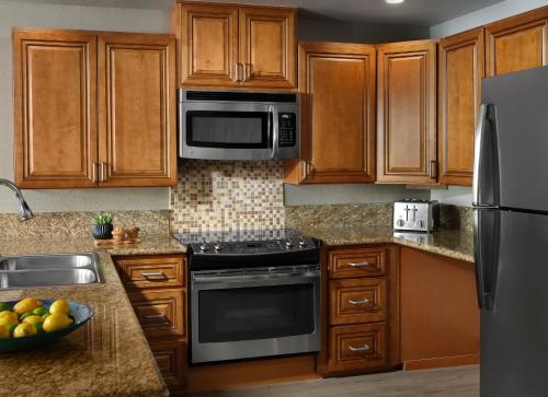 a kitchen with wooden cabinets and stainless steel appliances at Desert Oasis by Vacation Club Rentals in Cathedral City