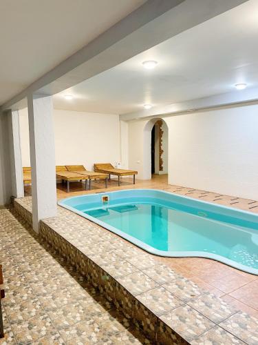 a large swimming pool in a room with a table and chairs at Hotel and Entertaiment Complex Vlada in Cherkasy