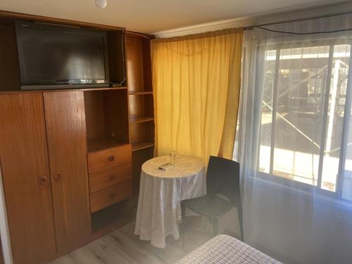 a room with a table and a tv and a window at Hotel Diaguitas Illapel in Illapel