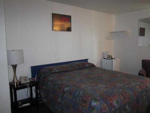 a hotel room with a bed and a phone on a table at Nisutlin Trading Post Motel in Teslin