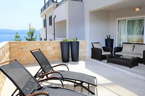 a patio with chairs and a couch on a balcony at Apartment Bol A6 with Pool from 45 EUR per Person in Bol