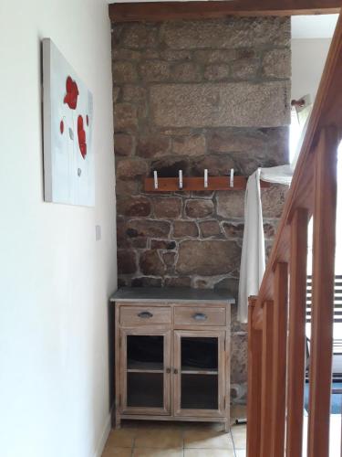 a room with a stone wall and a wooden cabinet at Gîte La Grange in Langoëlan