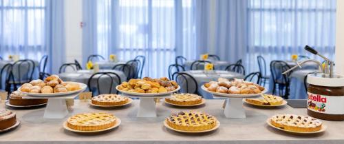 a table topped with bowls of pastries and pies at Hotel Mignon Riccione Fronte Mare in Riccione