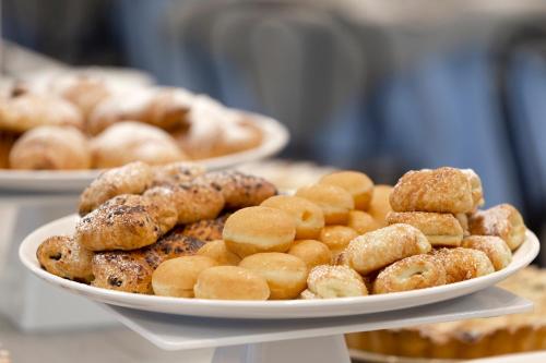 une assiette de beignets et autres pâtisseries sur une table dans l'établissement Hotel Mignon Riccione Fronte Mare, à Riccione