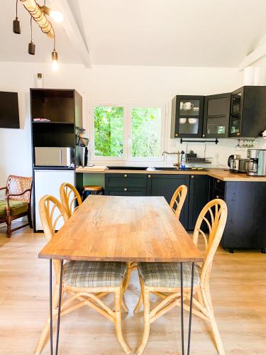 une cuisine avec une table et des chaises en bois dans l'établissement Atypique Chalet la rivière sous votre fenêtre, à Plésidy